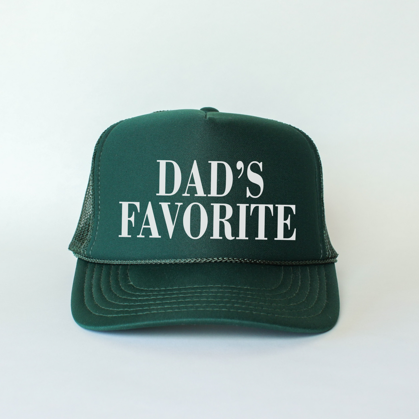 A person holding a black trucker hat with 'DAD'S FAVORITE' text in white font on the front panel.