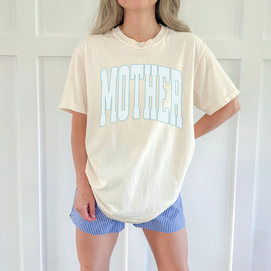 Relaxed fit ivory graphic tee with βMOTHERβ design, styled with striped shorts for everyday wear