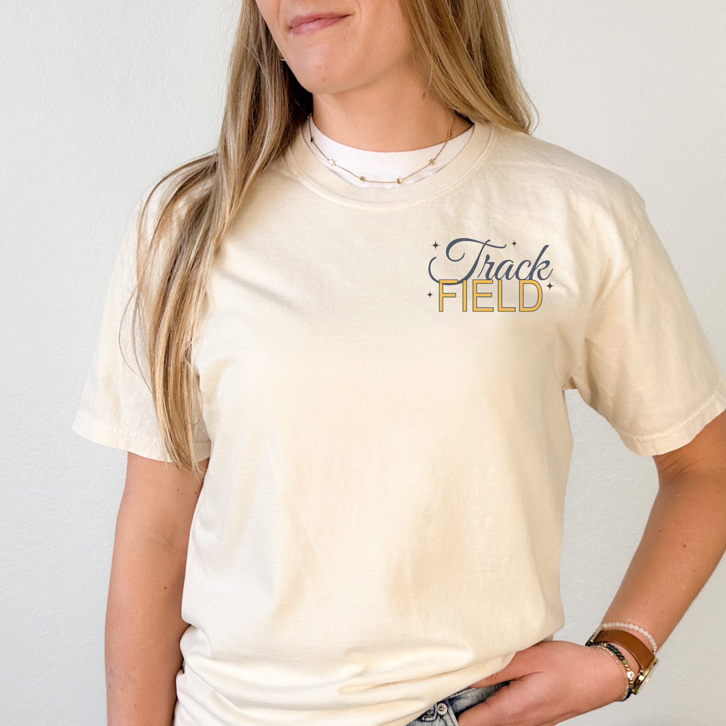 Person wearing a cream t-shirt with 'Track Field' text on a plain background