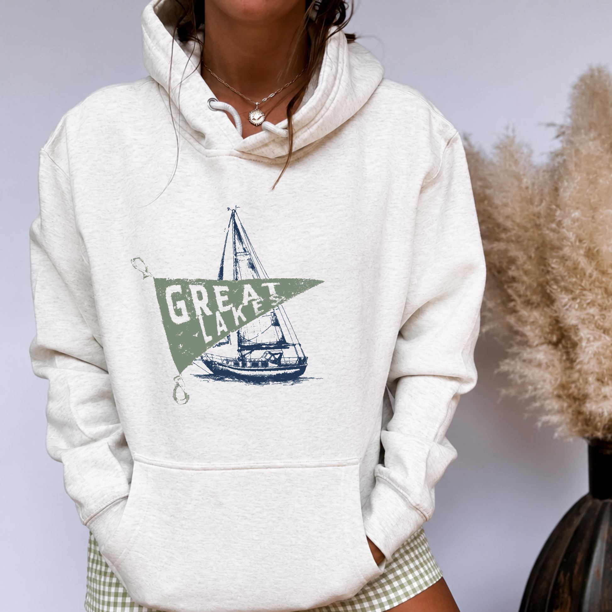 Great Lakes vintage sailboat graphic hoodie on oatmeal heather premium fleece worn with green gingham shorts.