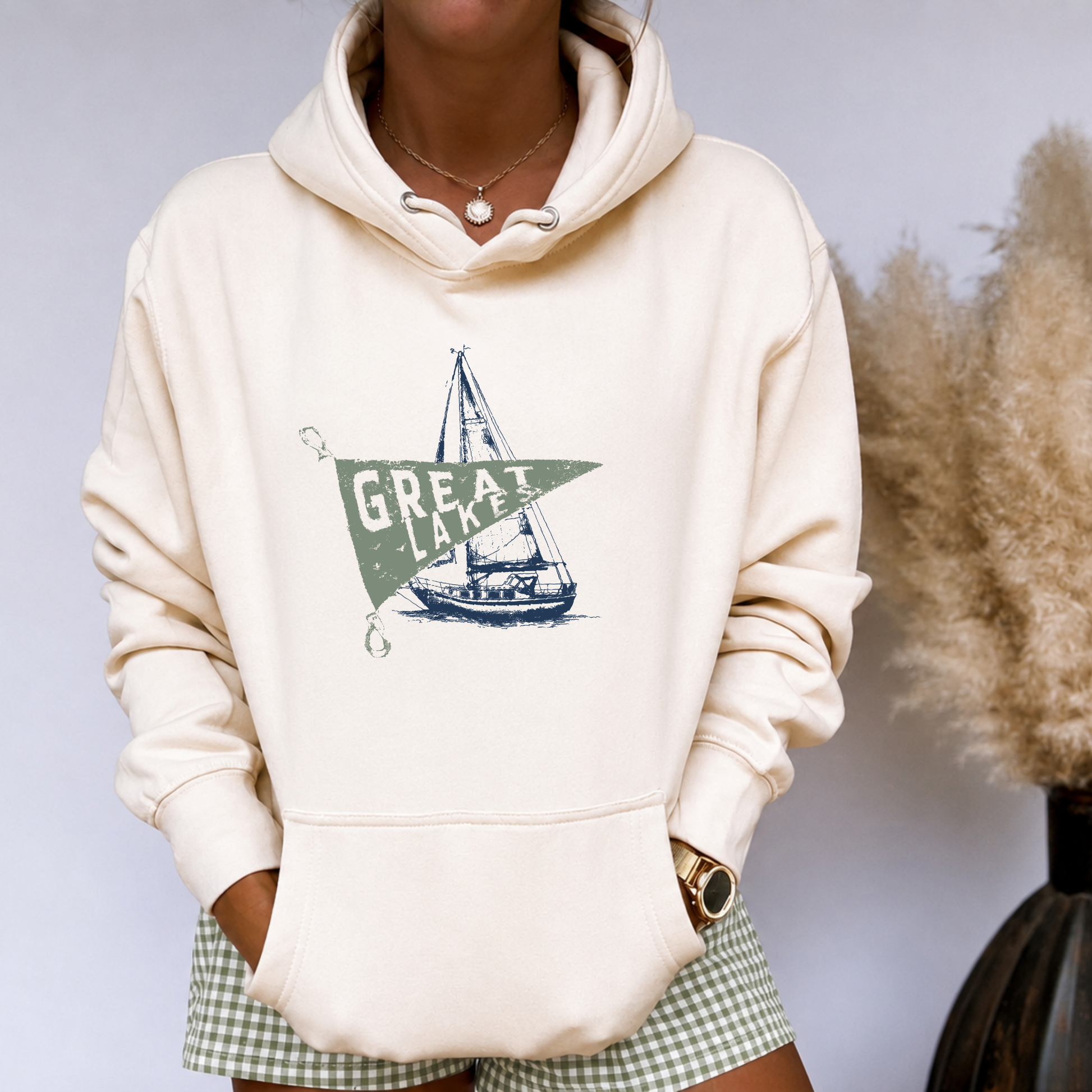 Model wearing sand-colored Great Lakes sailboat graphic hoodie with vintage coastal nautical artwork.