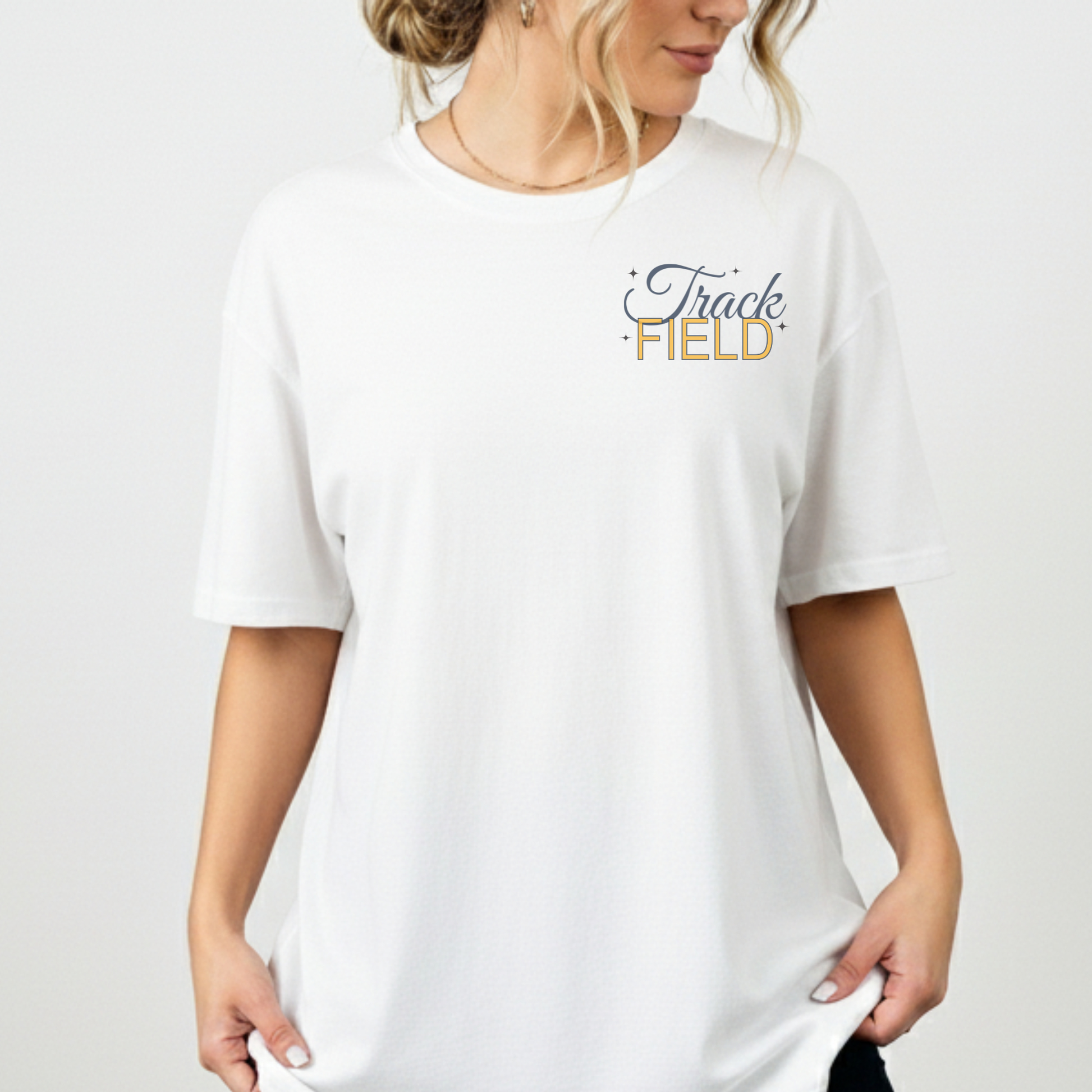 White t-shirt with 'Track Field' text worn by a person on a plain background