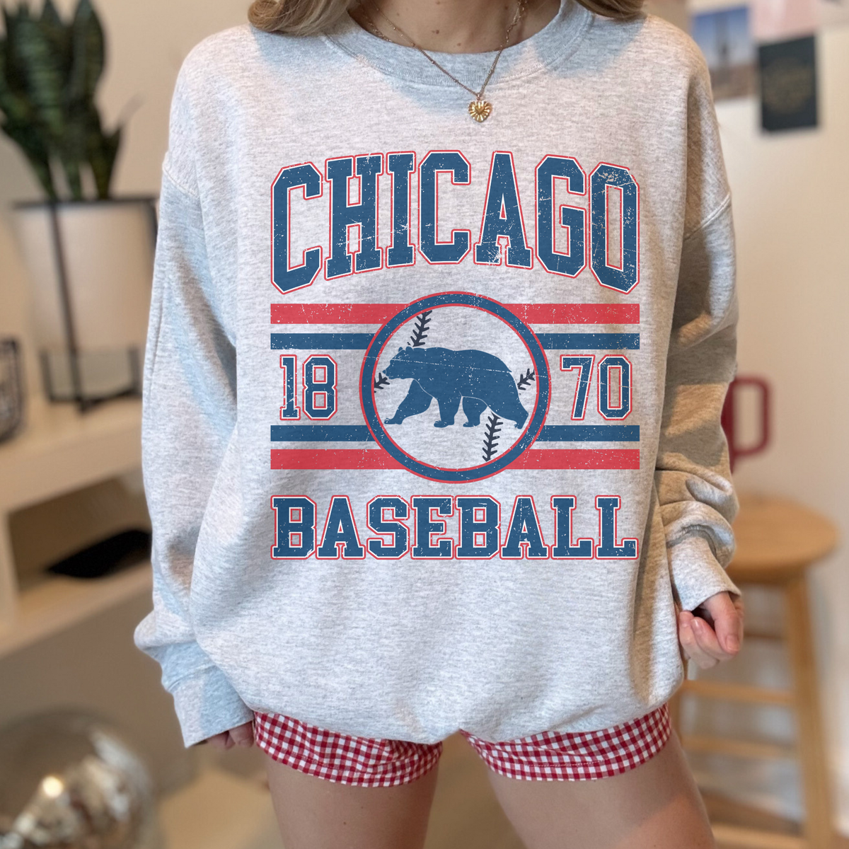 Person wearing a gray sweatshirt with 'Chicago Baseball' print and red checkered shorts.