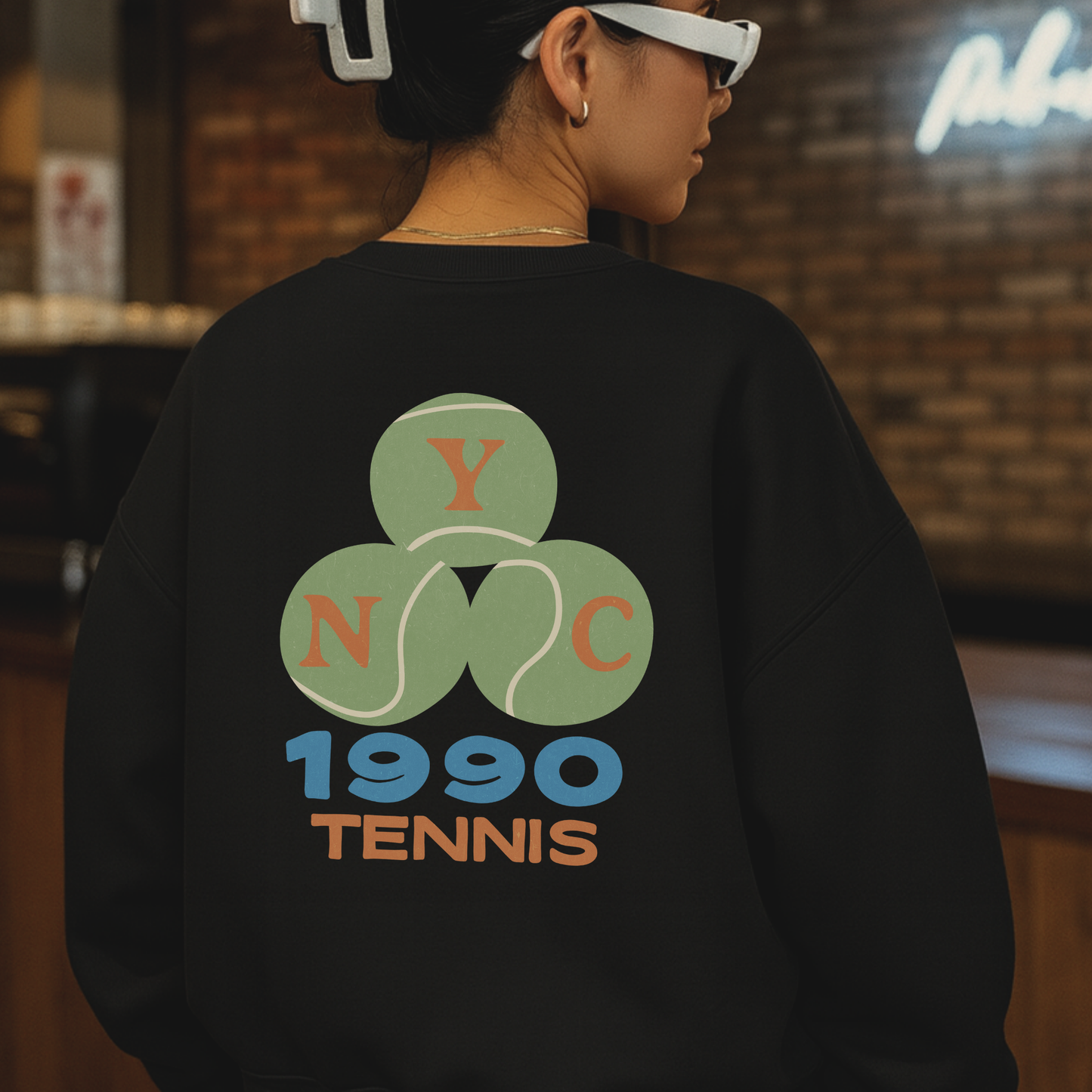 Model wearing black NYC 1990 tennis crewneck sweatshirt with large back graphic