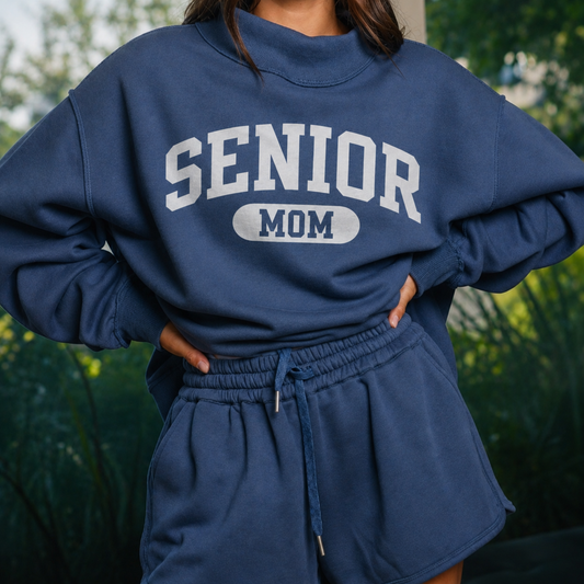 Navy Senior Mom 2027 reversible mock neck sweatshirt featuring solid white SENIOR MOM collegiate graphic on the front.
