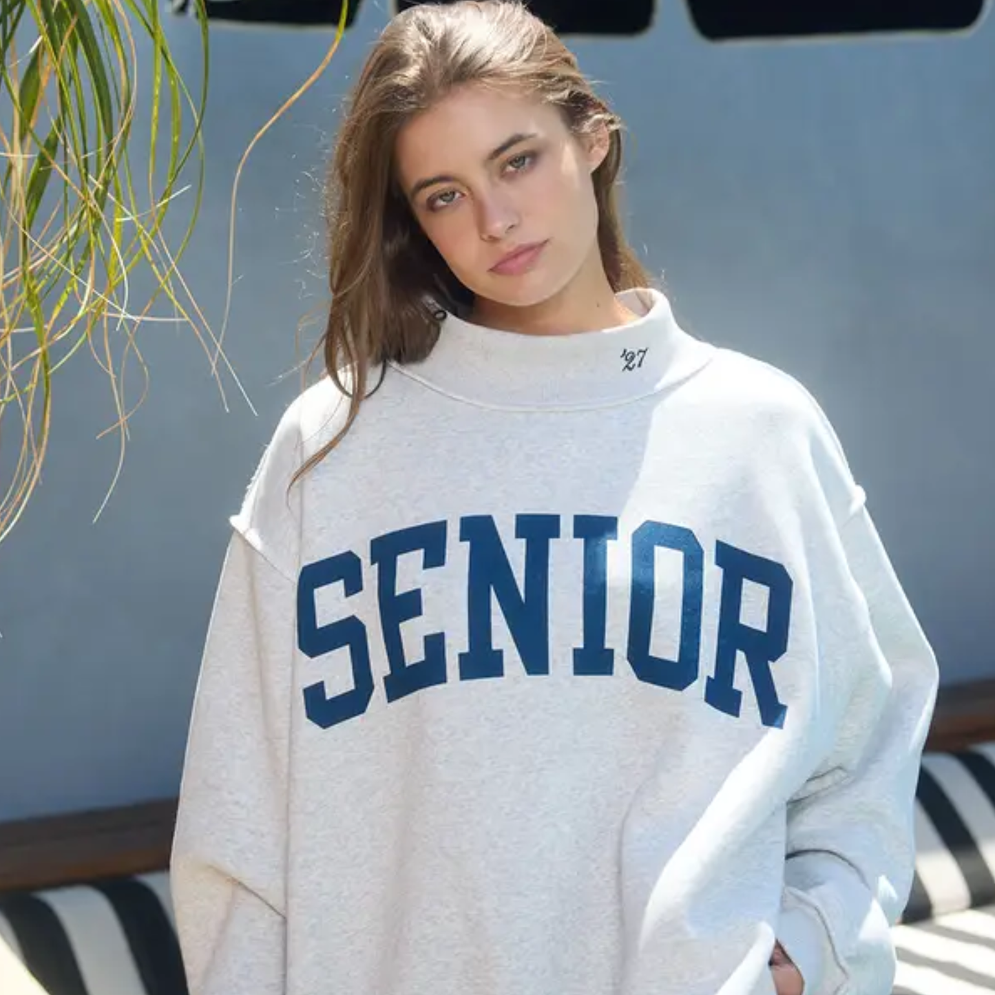 Senior 2027 reversible mock neck sweatshirt in oatmeal heather featuring oversized navy varsity lettering and embroidered “’27” detail on the collar.