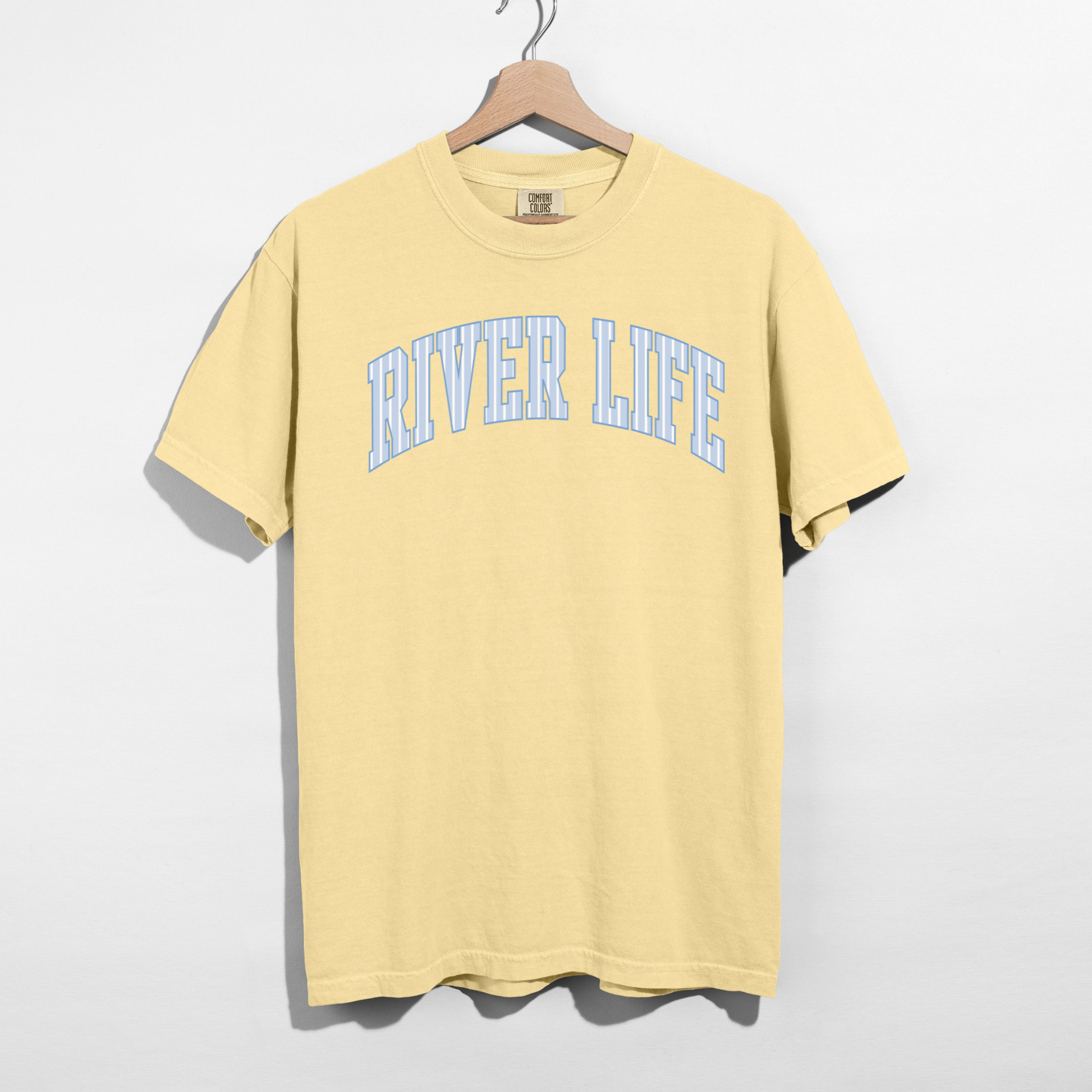 butter yellow river life graphic t shirt with blue collegiate lettering hanging on hanger product image
