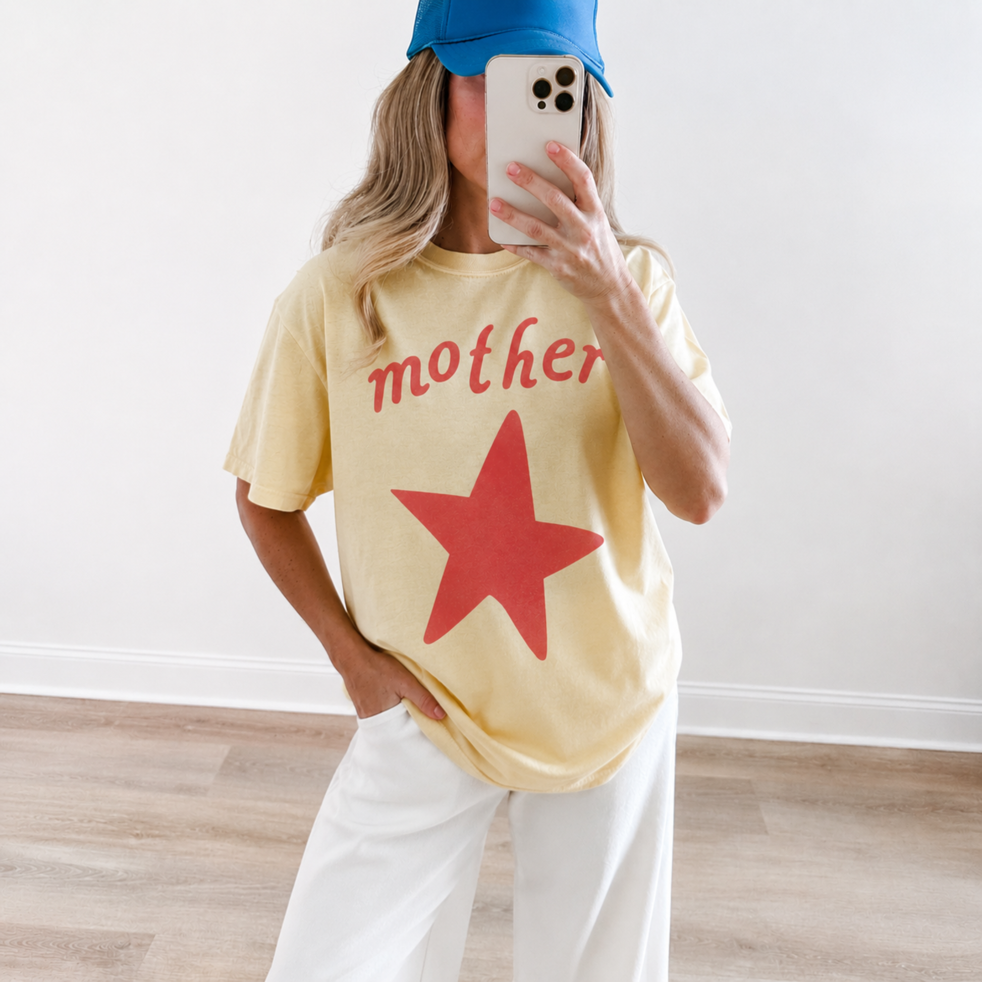Butter yellow Mother graphic t-shirt with oversized coral star and vintage-inspired lettering, styled with casual white pants for everyday mom fashion.