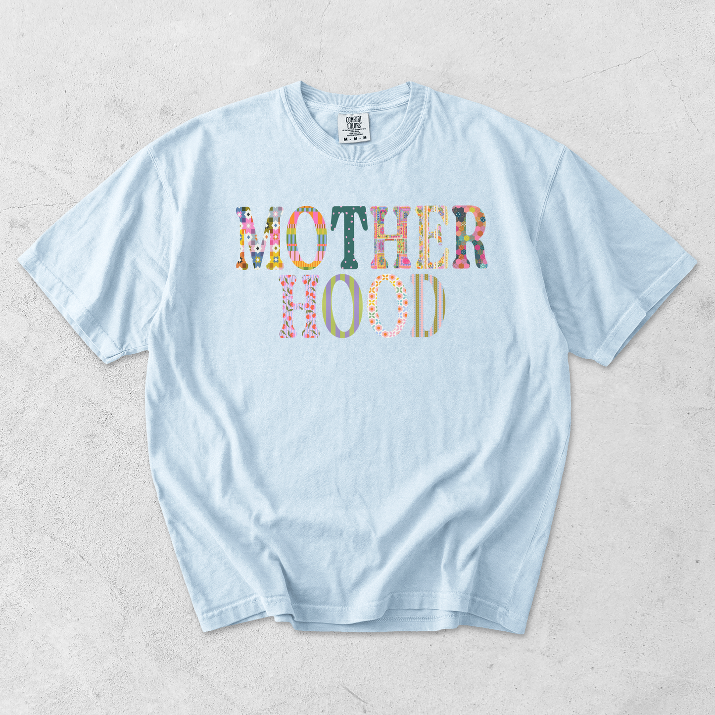 Chambray blue Comfort Colors motherhood graphic tee with colorful patterned motherhood graphic on front.