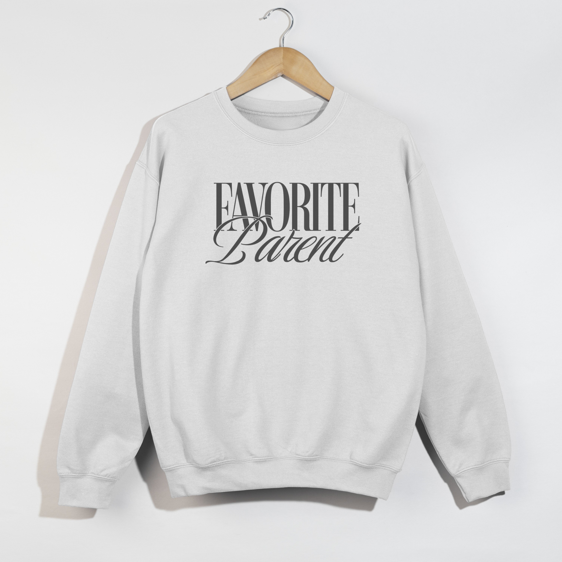 White Favorite Parent crewneck sweatshirt with bold black graphic print hanging on wooden hanger