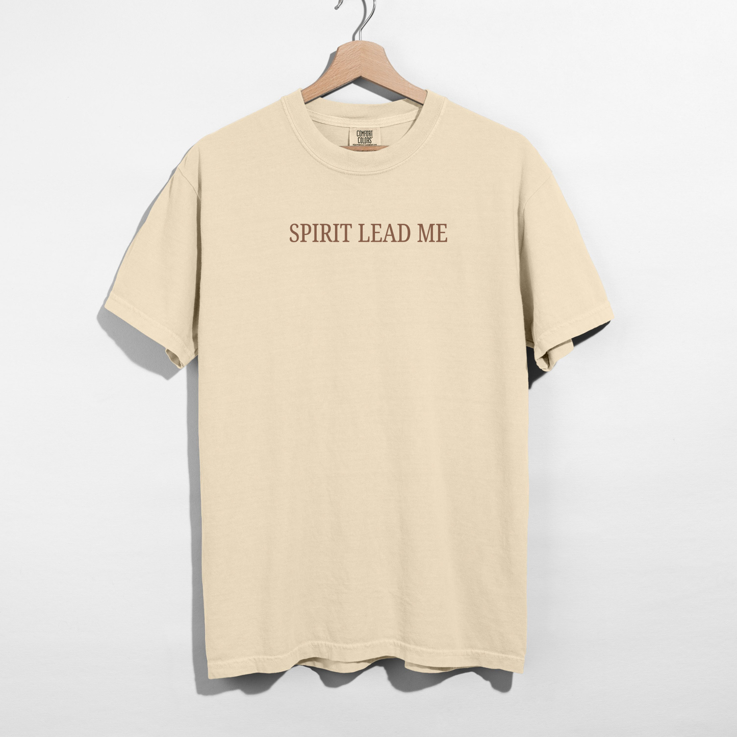 Beige t-shirt with 'SPIRIT LEAD ME' text on a hanger against a white background