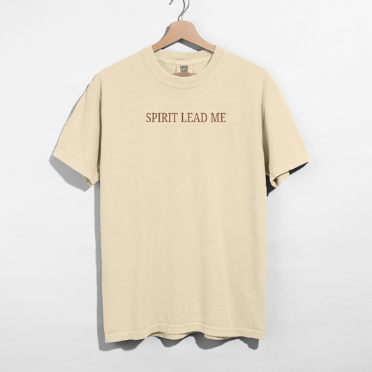 Beige t-shirt with 'SPIRIT LEAD ME' text on a hanger against a white background