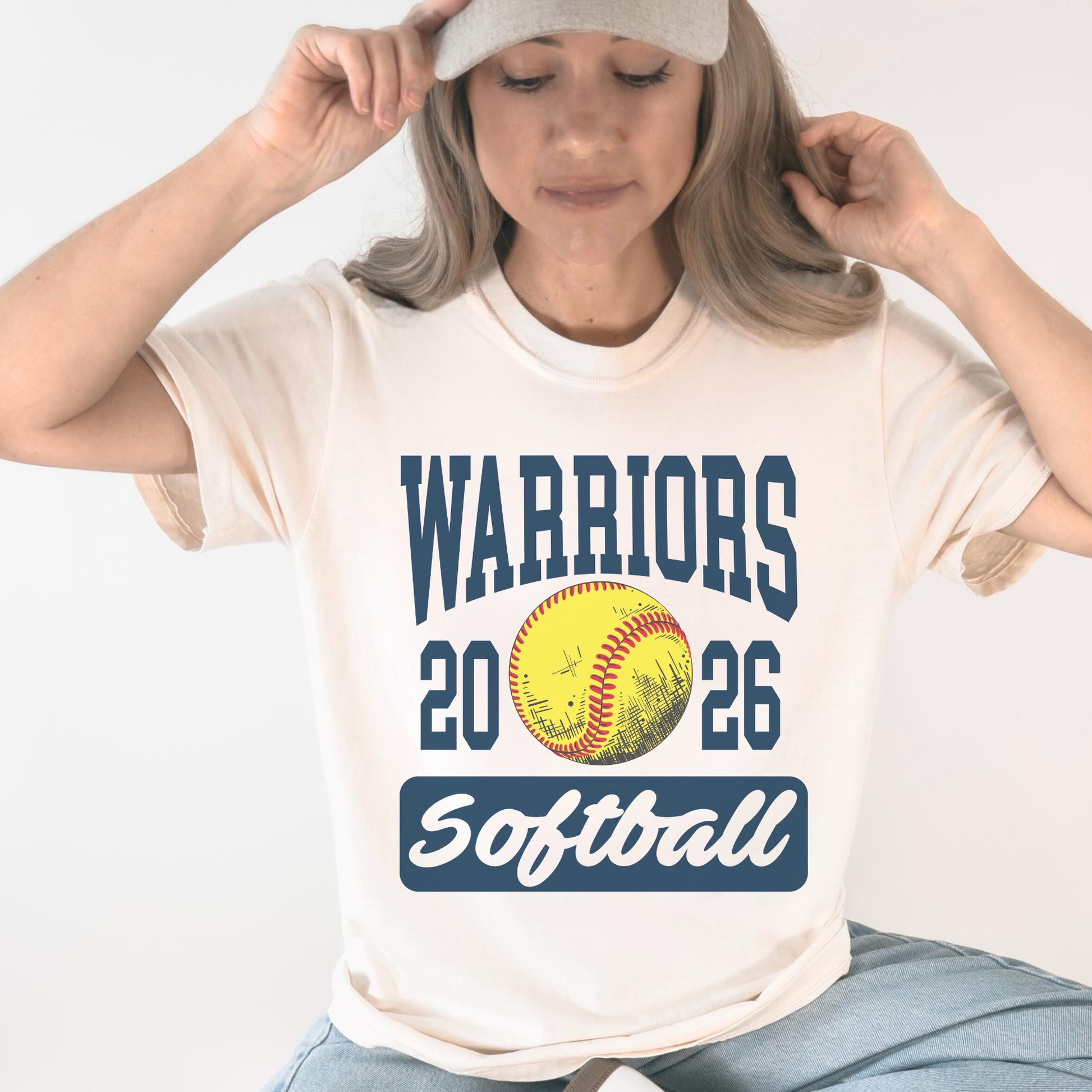 Woman wearing ivory Warriors Softball 2026 unisex school spirit t shirt with vintage softball graphic