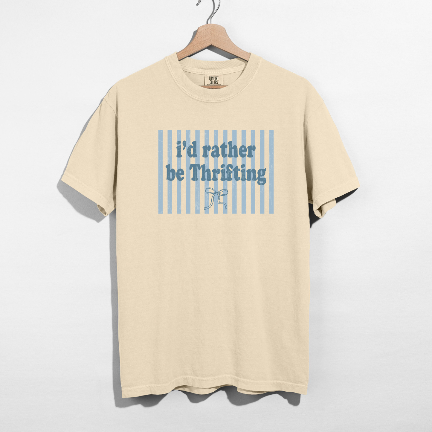 Sand Comfort Colors t-shirt with blue striped “I’d Rather Be Thrifting” graphic on hanger