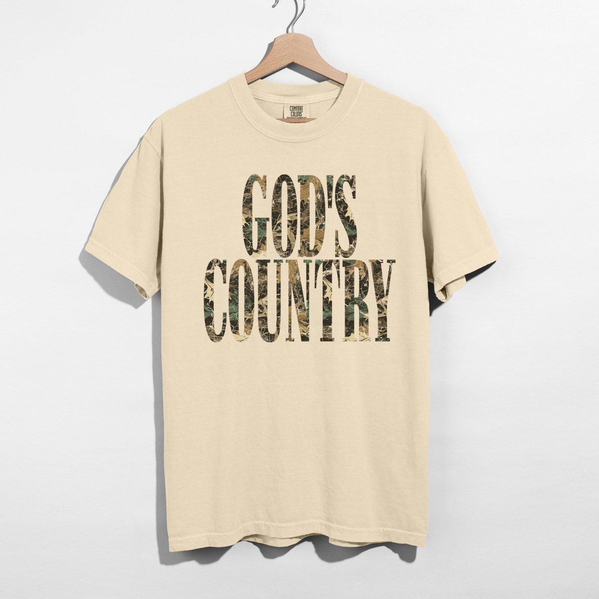Ivory God’s Country camo graphic tee with olive brown and tan woodland camouflage lettering