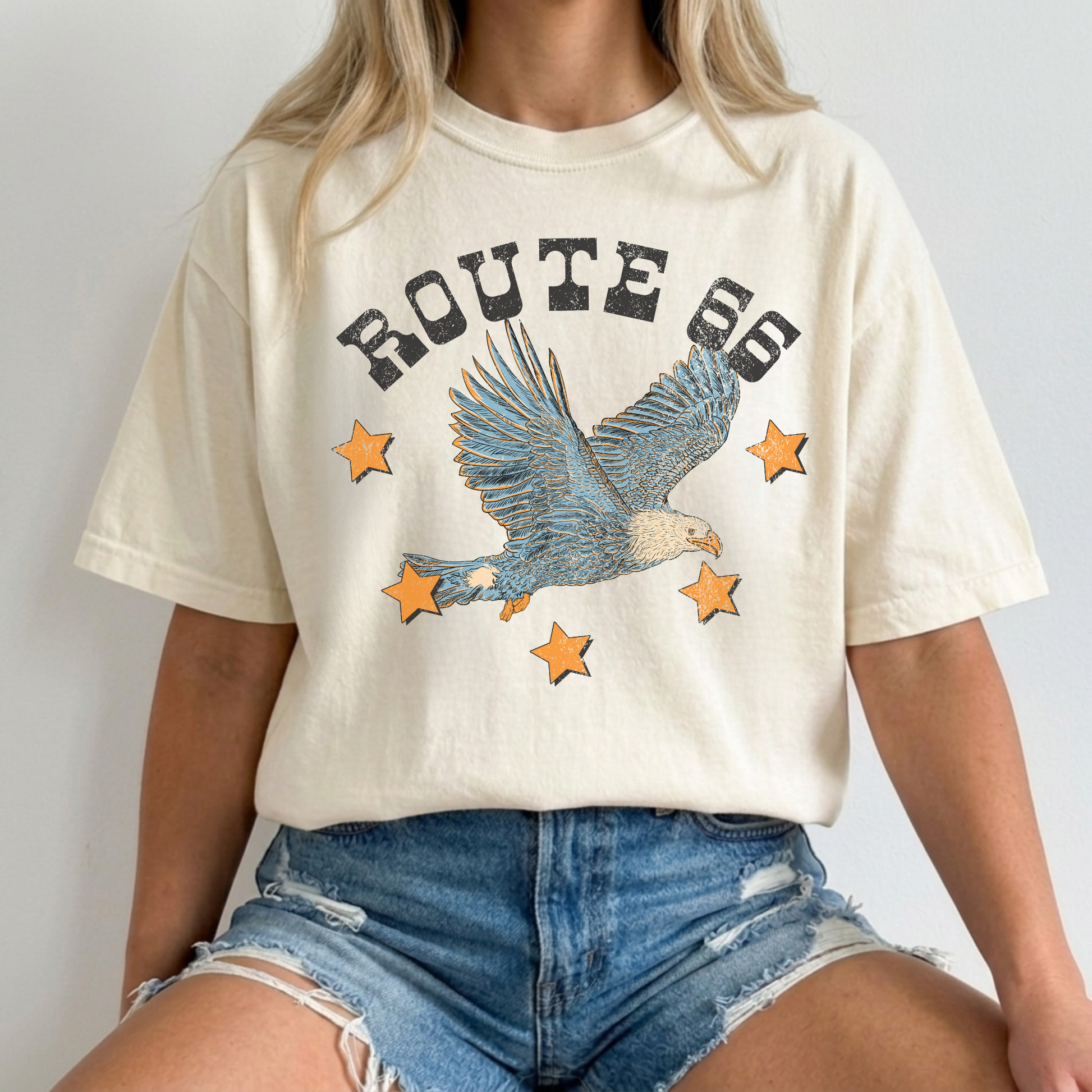 Closeup ivory Comfort Colors Route 66 eagle graphic t-shirt paired with distressed denim shorts