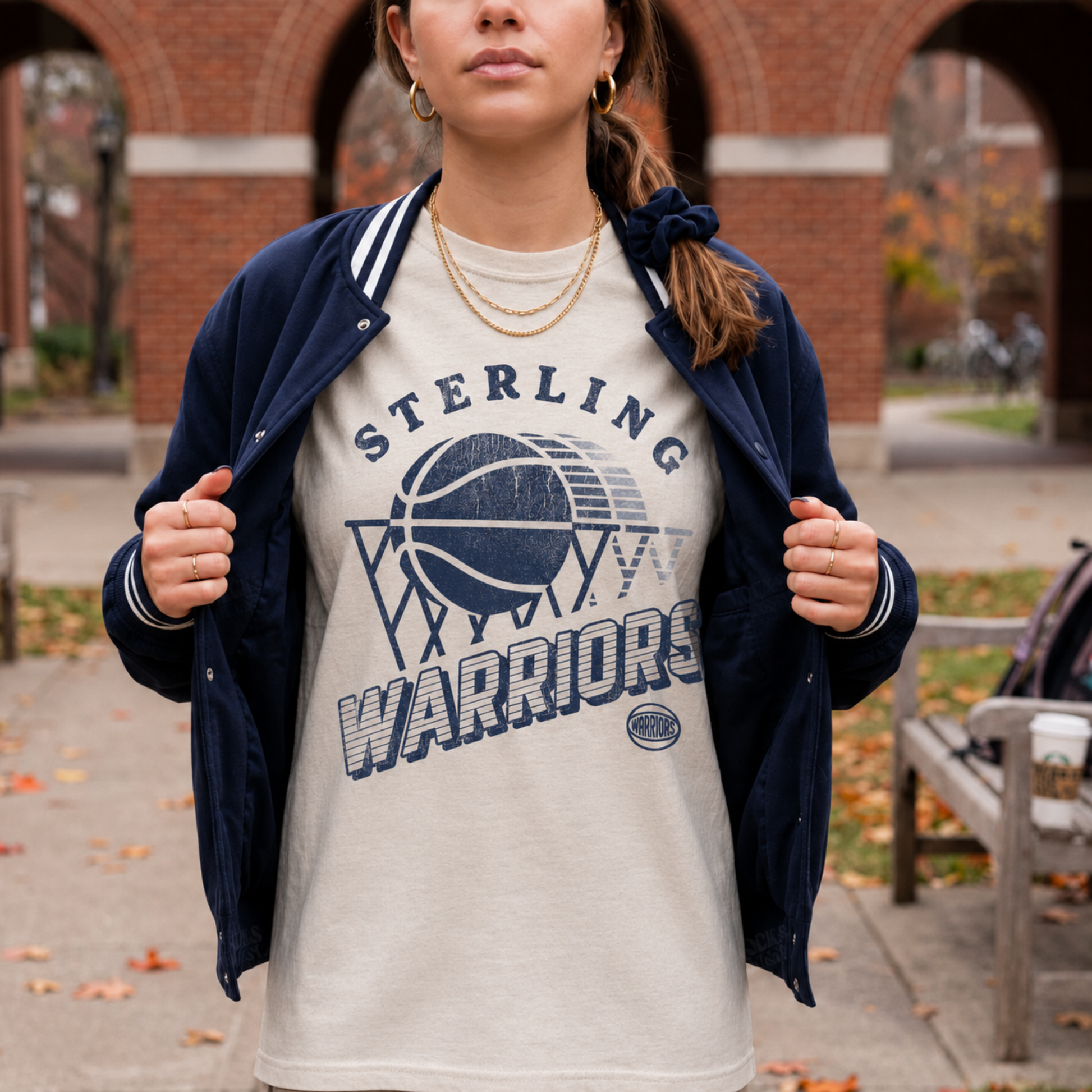 Lifestyle photo of Sterling Warriors retro basketball Comfort Colors t-shirt layered with a navy varsity jacket.