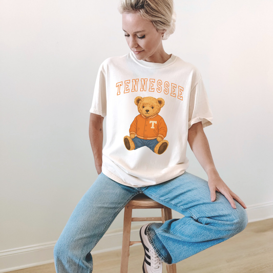 Woman wearing an ivory Tennessee teddy bear graphic tee with vintage orange collegiate lettering and cute game day teddy bear design.