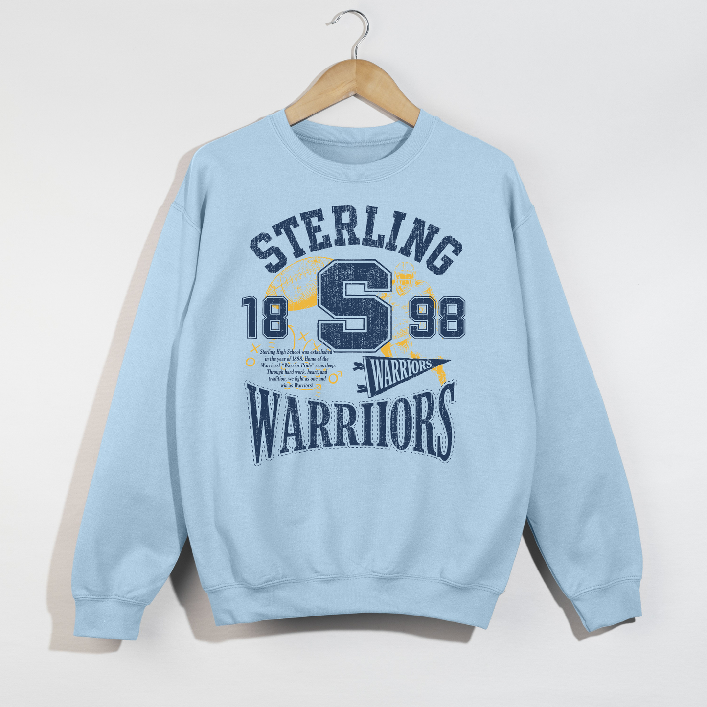 Light blue Sterling Warriors vintage football sweatshirt featuring distressed collegiate graphics, football artwork, and retro navy and gold school spirit design.
