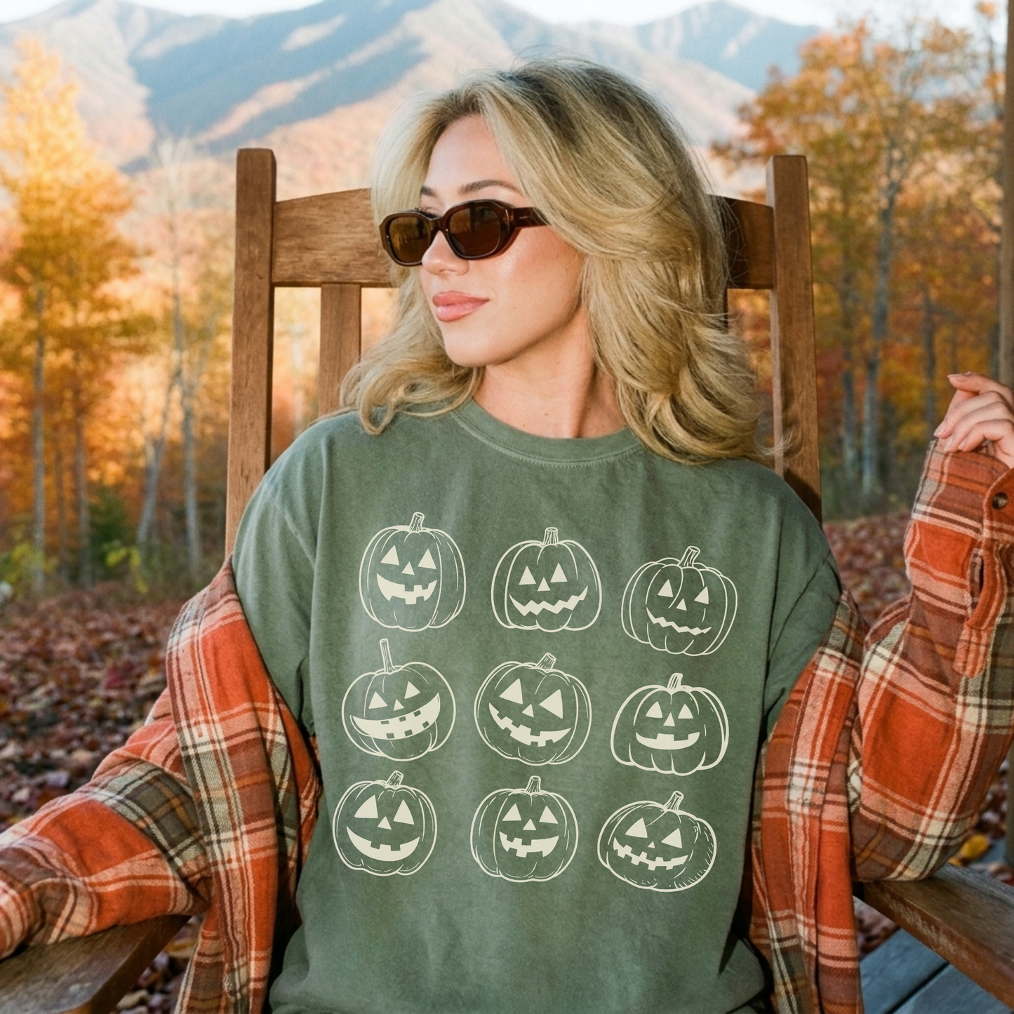 Moss green Comfort Colors pumpkin graphic tee with vintage jack o lantern design layered with a cozy fall flannel in autumn mountains.