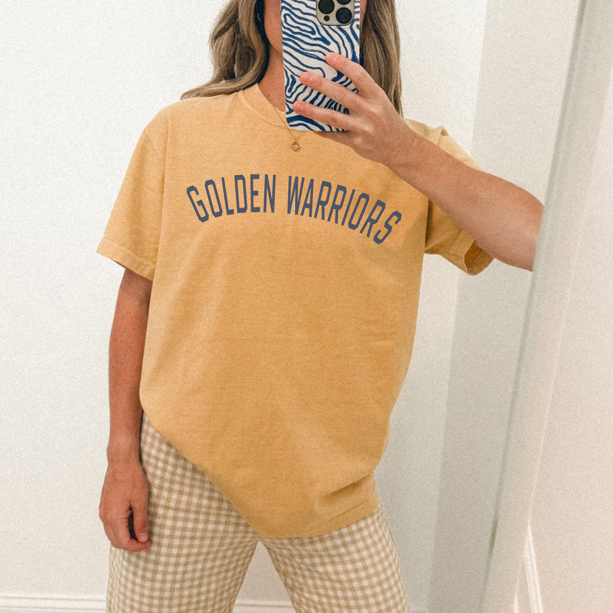 Person wearing a mustard yellow 'Golden Warriors' t-shirt and plaid pants.
