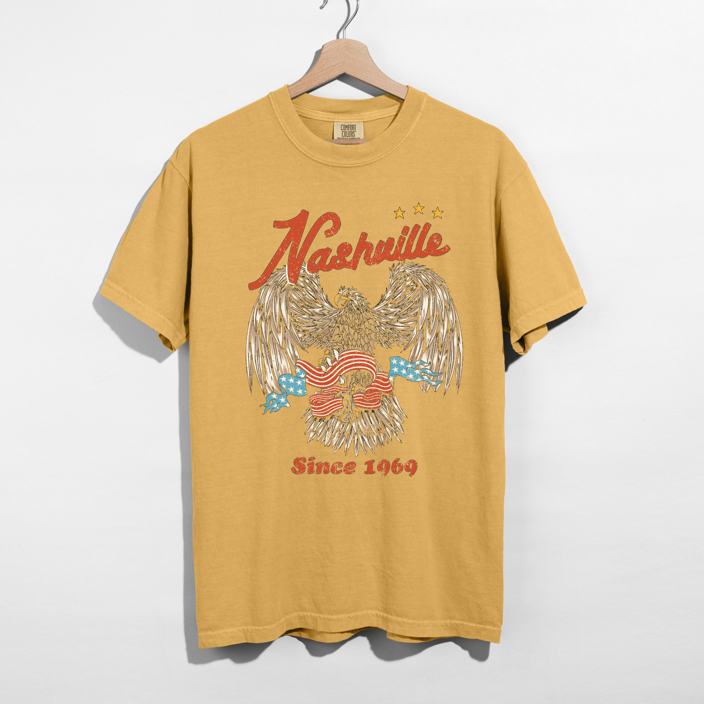Mustard Nashville graphic t-shirt with vintage eagle design hanging on hanger retro country shirt