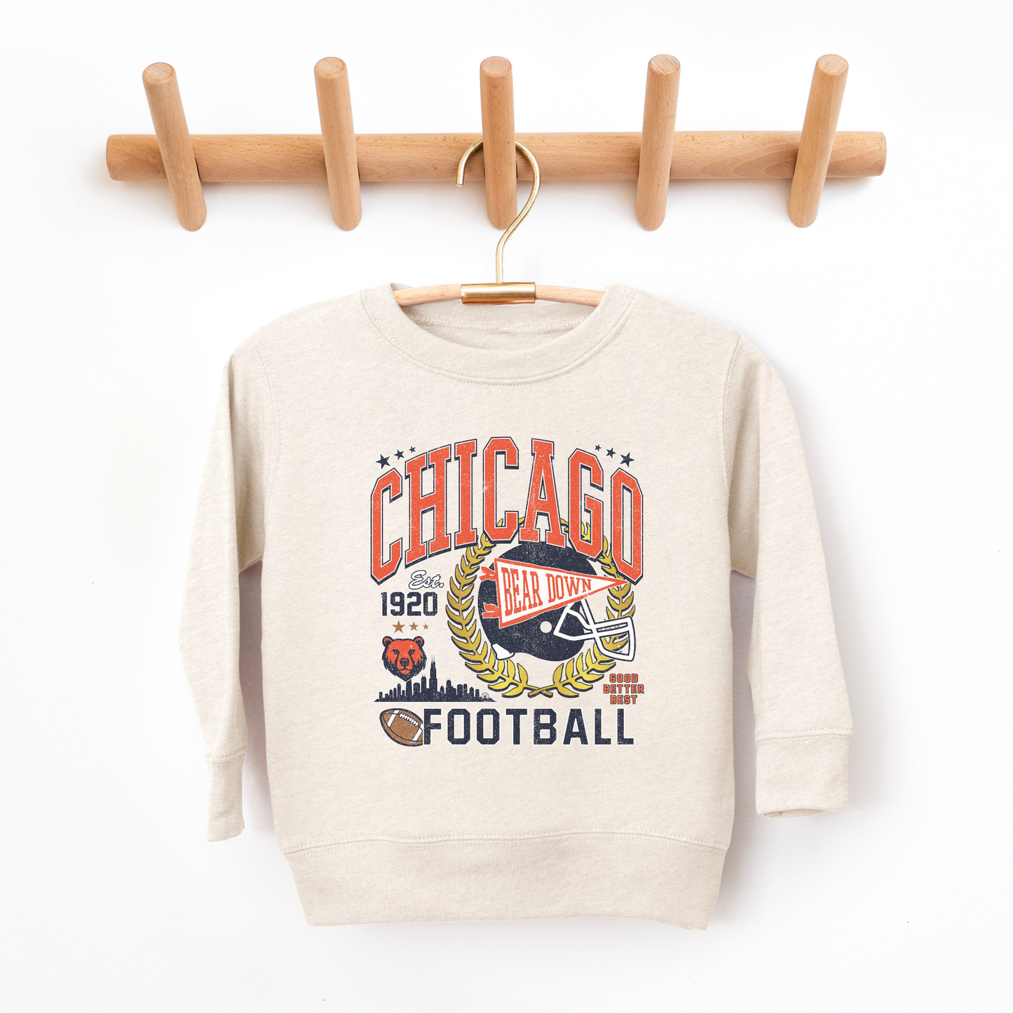 Beige sweatshirt with Chicago-themed design hanging on a wooden rack against a white background