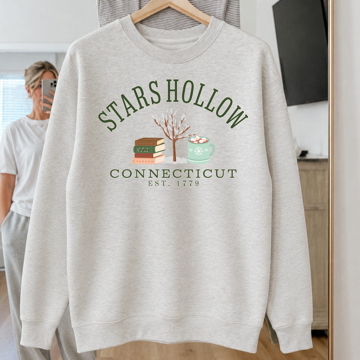 Stars Hollow Connecticut premium winter sweatshirt with stacked books snow covered tree and mint hot cocoa mug