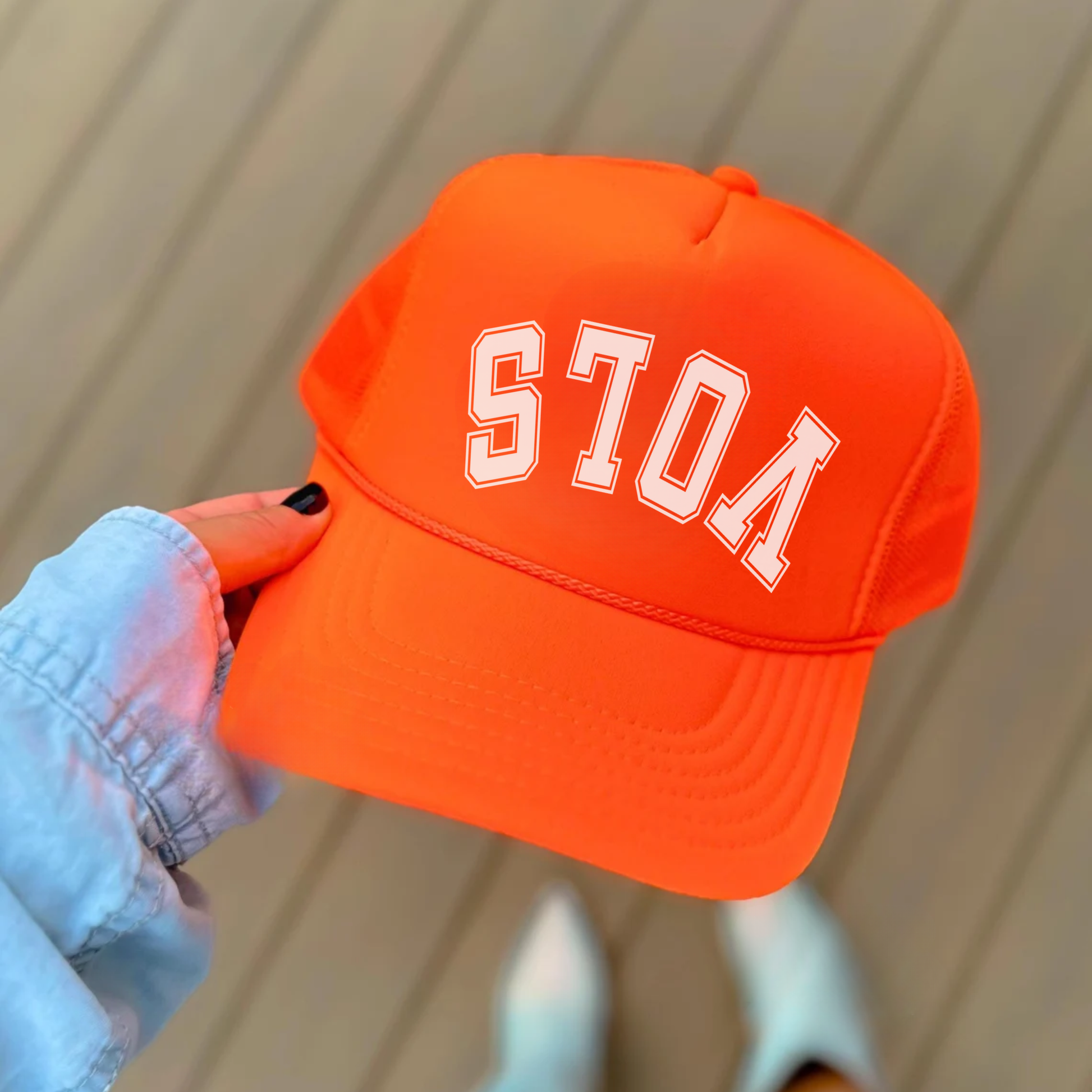 Orange cap with 'vols' text held by a person against a neutral background