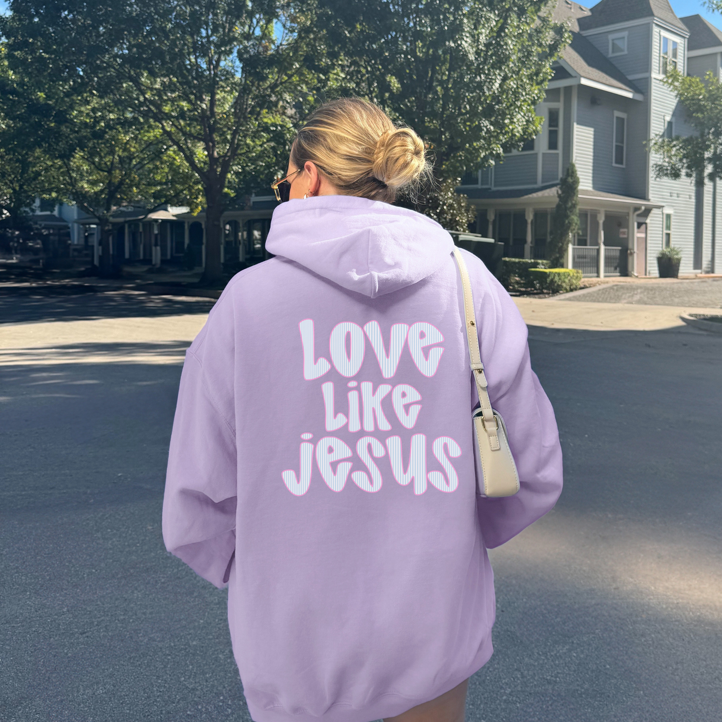 Woman wearing orchid hoodie with large “Love Like Jesus” back print, Christian faith sweatshirt.