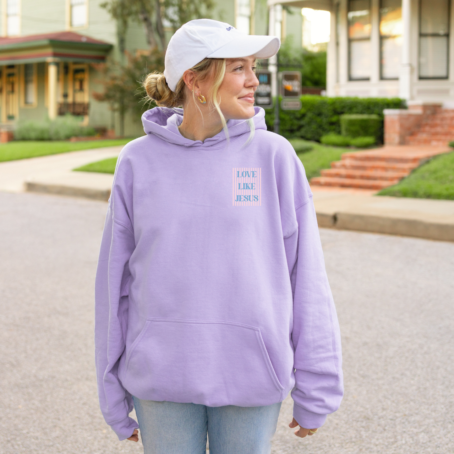 Woman wearing orchid hoodie with small striped “Love Like Jesus” front print, Christian graphic hoodie.