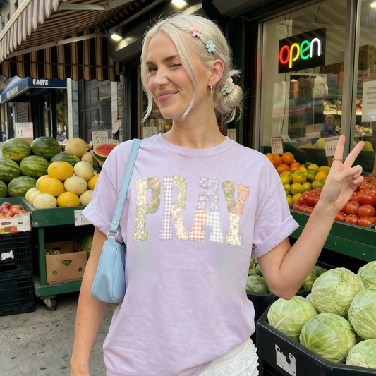 Woman wearing purple PRAY faux patchwork graphic tee styled casually outdoors