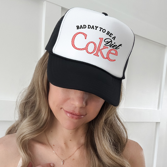 Woman wearing black and white foam trucker hat with “Bad Day to Be a Diet Coke” funny retro design