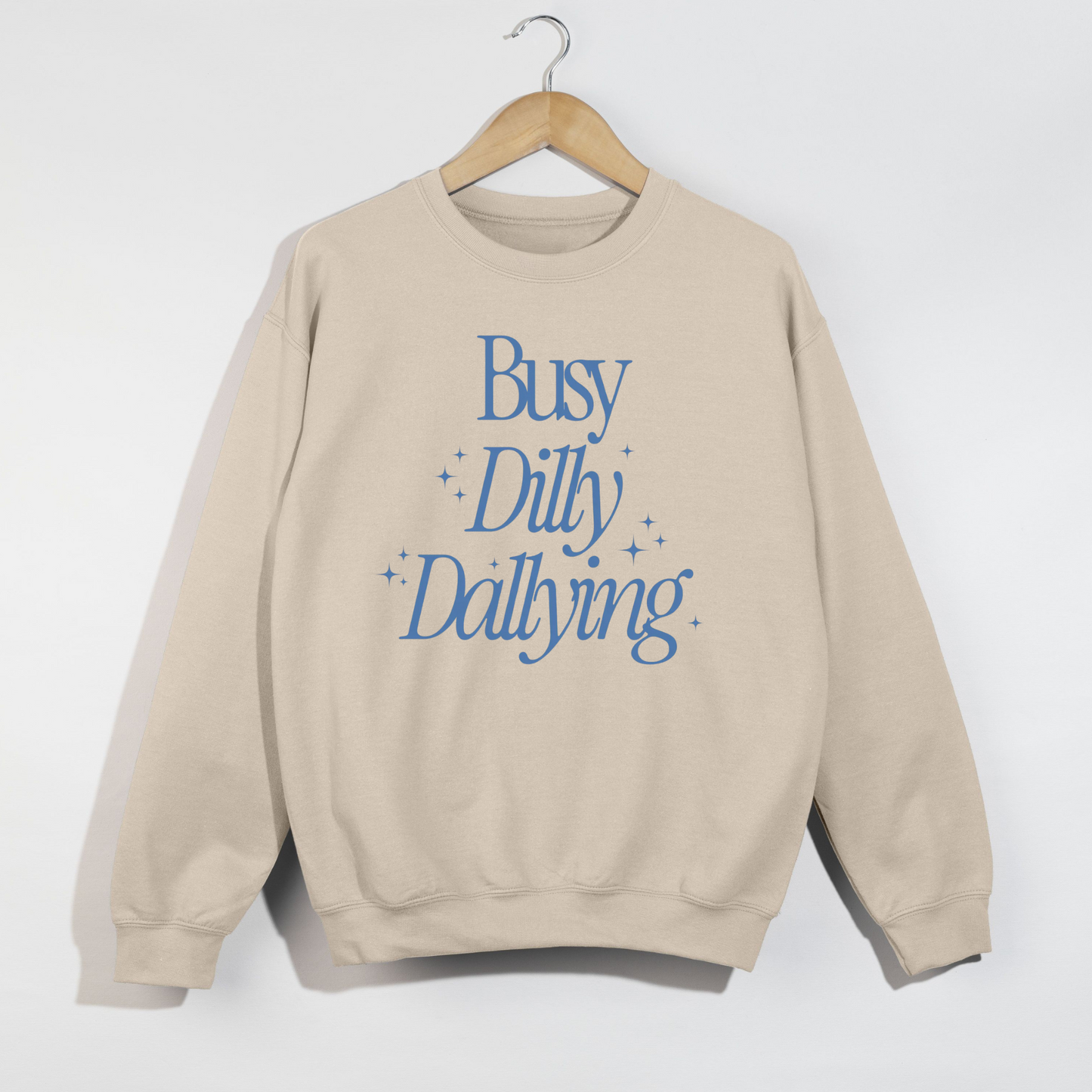 Beige sweatshirt with blue text 'Busy Dilly Dallying' on a white background
