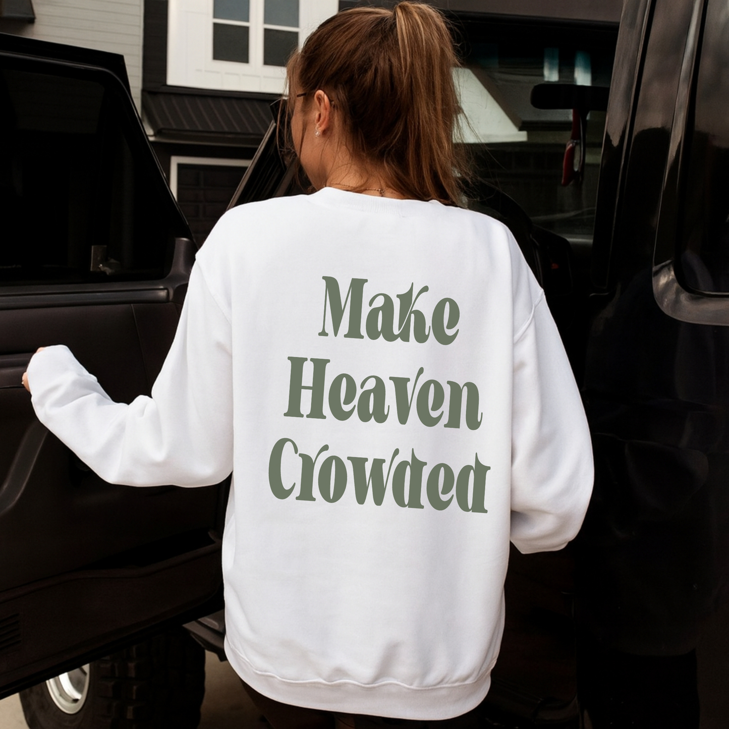 “Woman wearing white sweatshirt with large green ‘Make Heaven Crowded’ print on the back while stepping out of vehicle.”