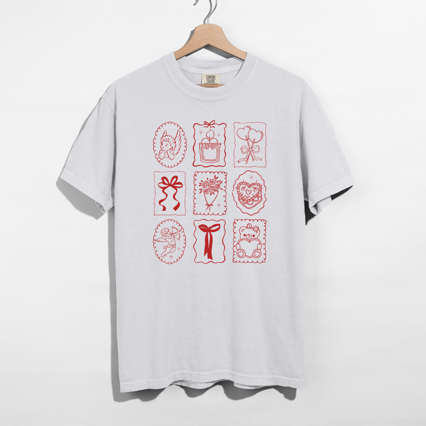 White Comfort Colors tee with red Valentine stamp icons graphic on hanger.