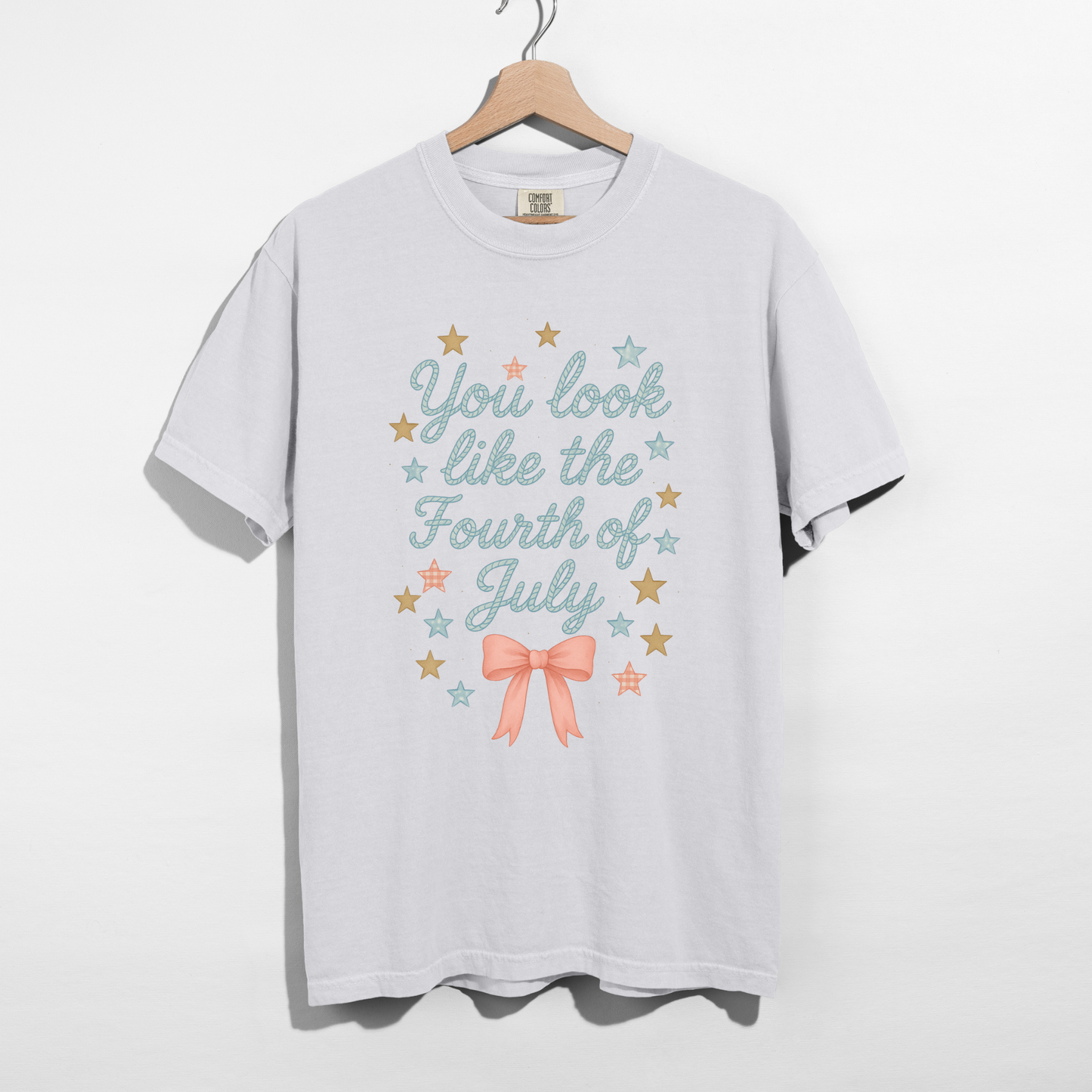 White t-shirt with 'You look like the Fourth of July' text and stars on a hanger against a white background