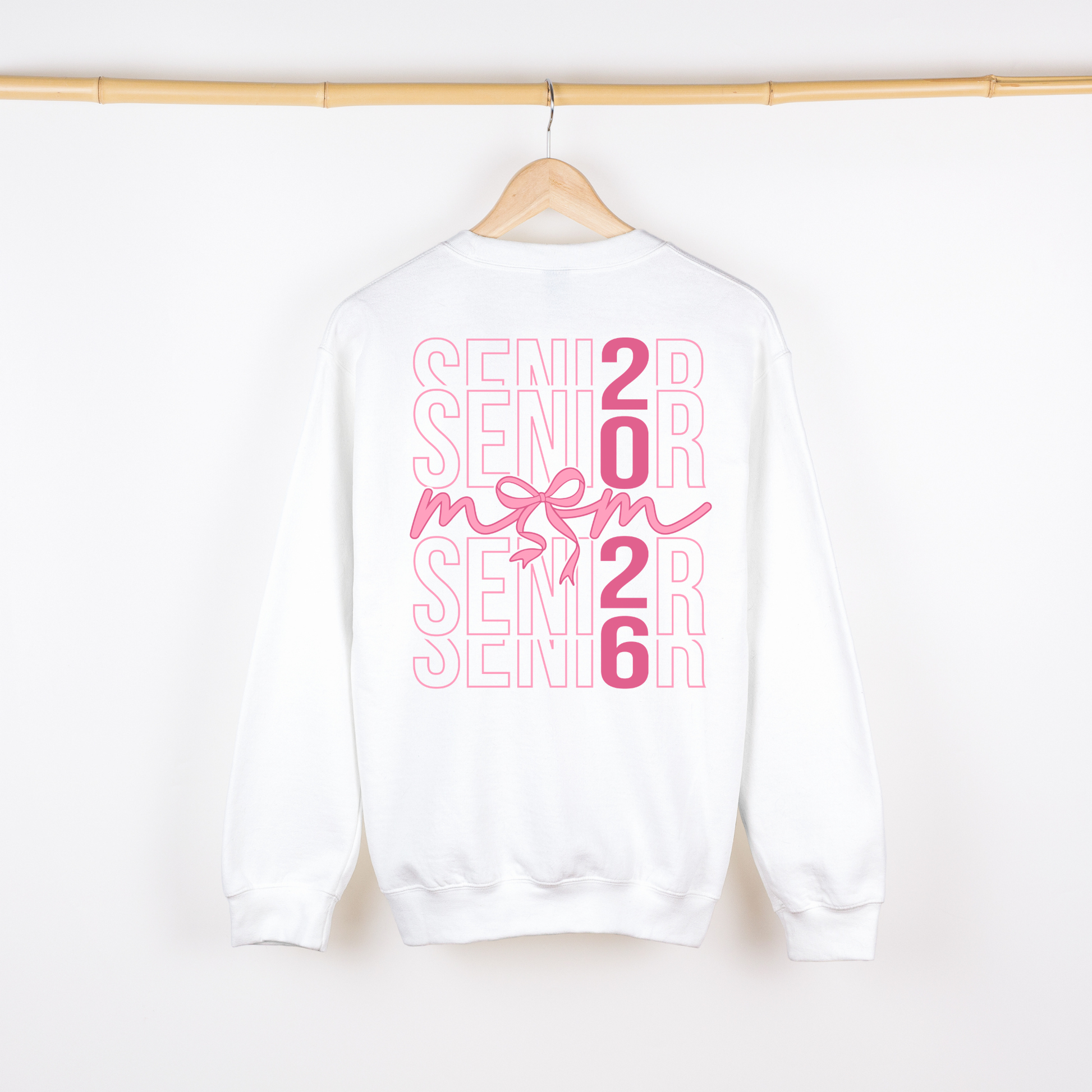 White sweatshirt with pink 'Senior 2026' text on a hanger against a white background