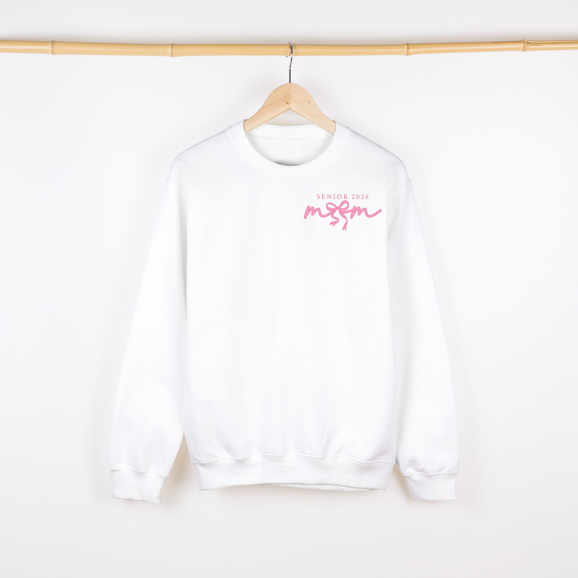 White sweatshirt with pink text on a wooden hanger against a white background