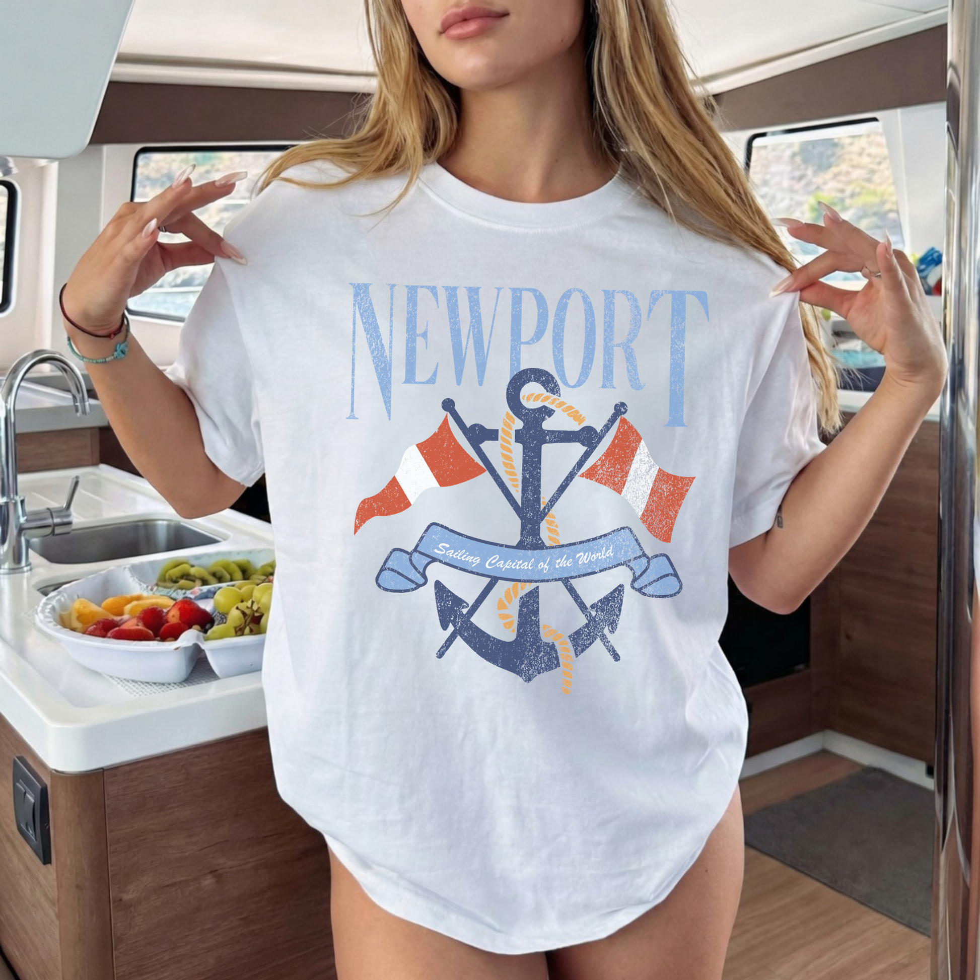 Woman wearing white Newport sailing graphic tee with anchor design indoors near kitchen