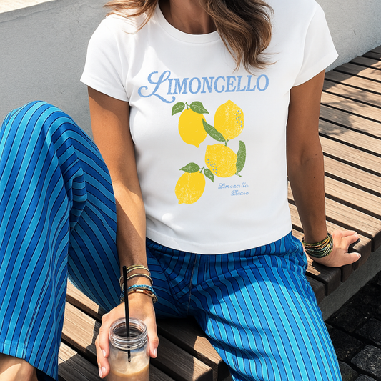 Woman wearing white Limoncello Please baby tee featuring vintage lemon graphic and soft blue lettering with bright summer outfit