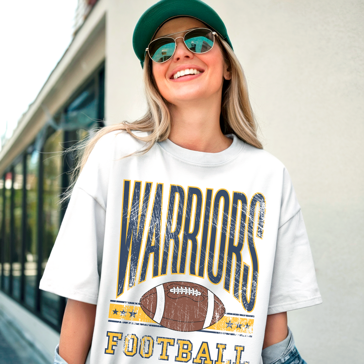 Person wearing a 'Warriors Football' t-shirt with sunglasses and a cap.