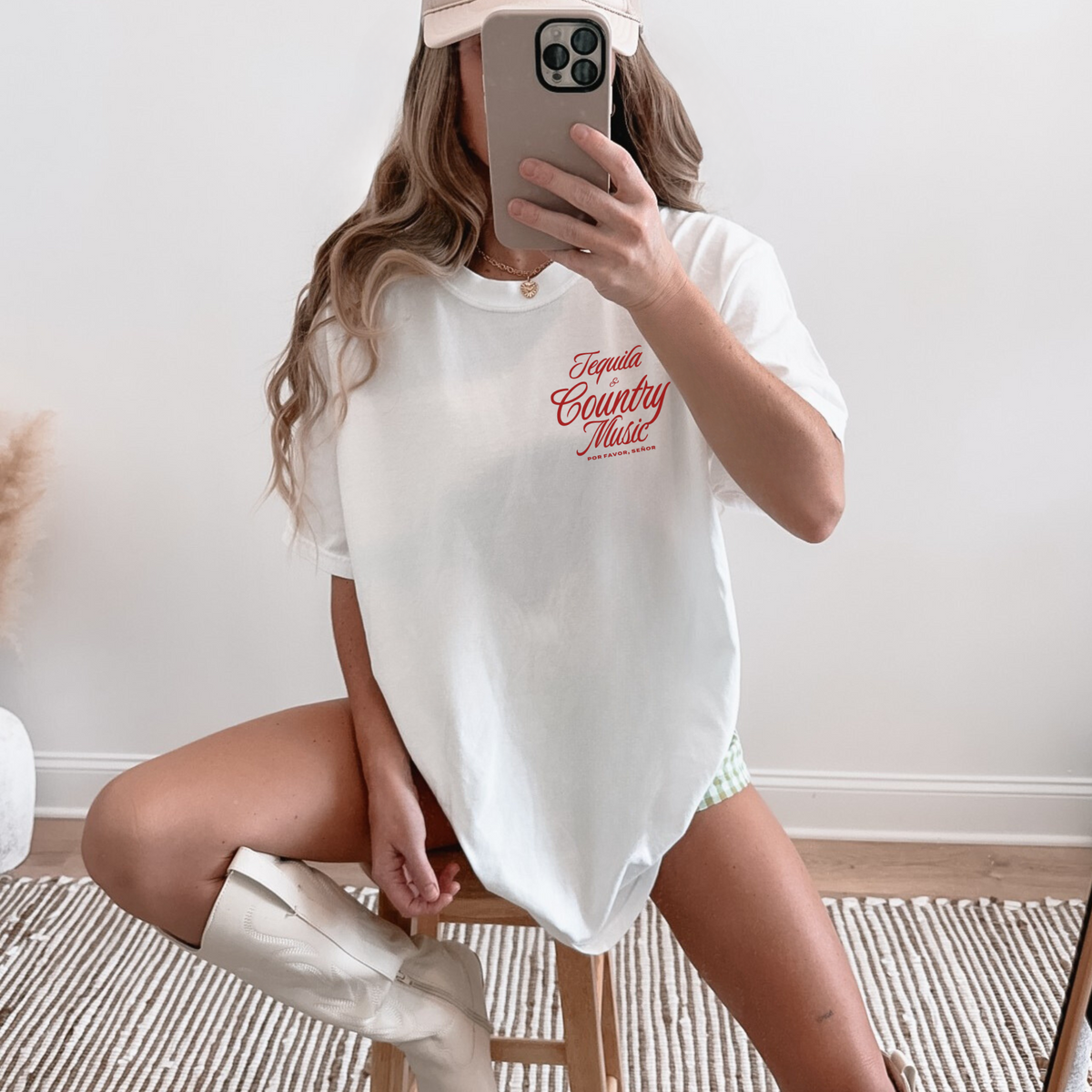 Person wearing a white t-shirt with red text, sitting on a stool indoors.