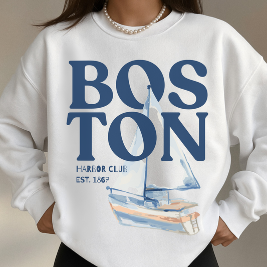 Woman wearing white Boston Harbor Club coastal sailboat sweatshirt with oversized nautical graphic and pearl necklace styling