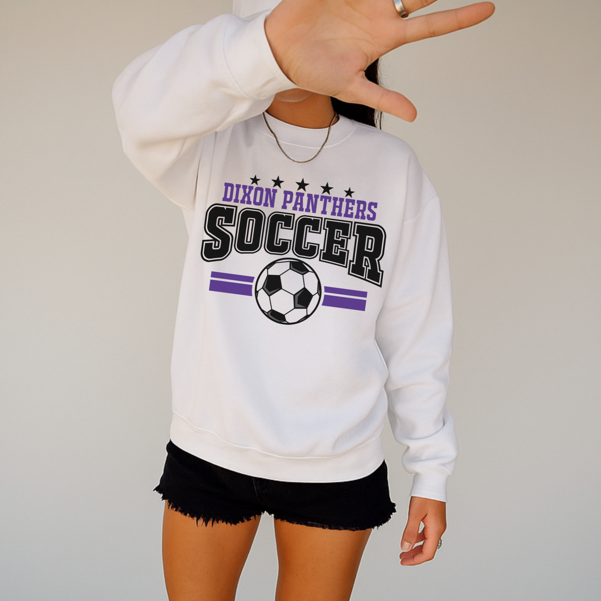 Woman wearing white Dixon Panthers varsity soccer crewneck sweatshirt with purple and black design