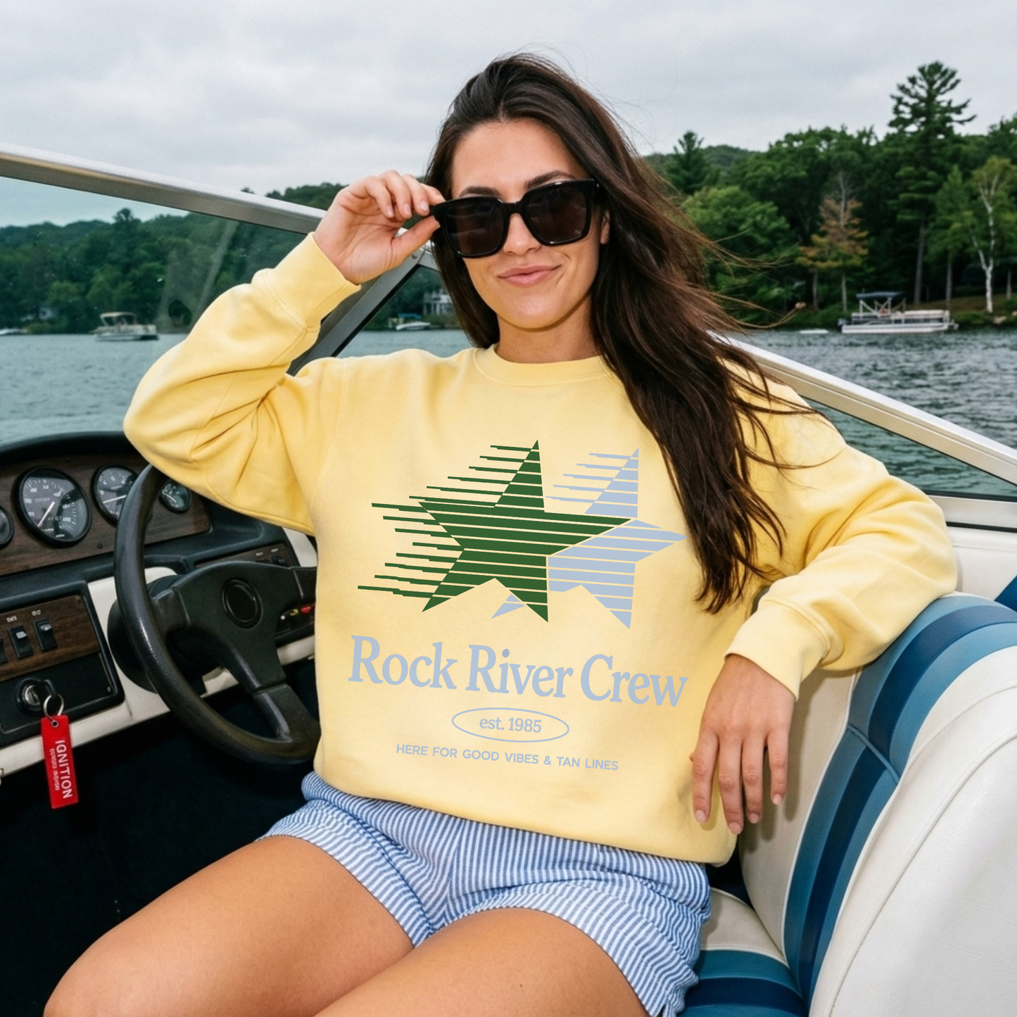 Woman wearing a yellow 'Rock River Crew' sweatshirt on a boat